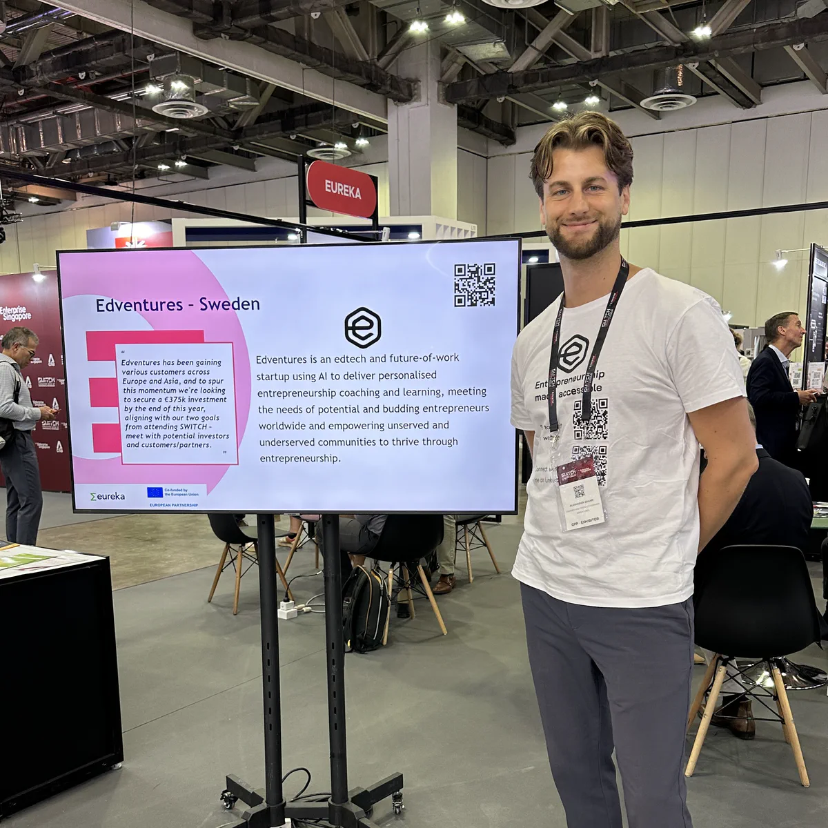 Edventures booth at SWITCH in Singapore 2024 with founder standing beside a display screen